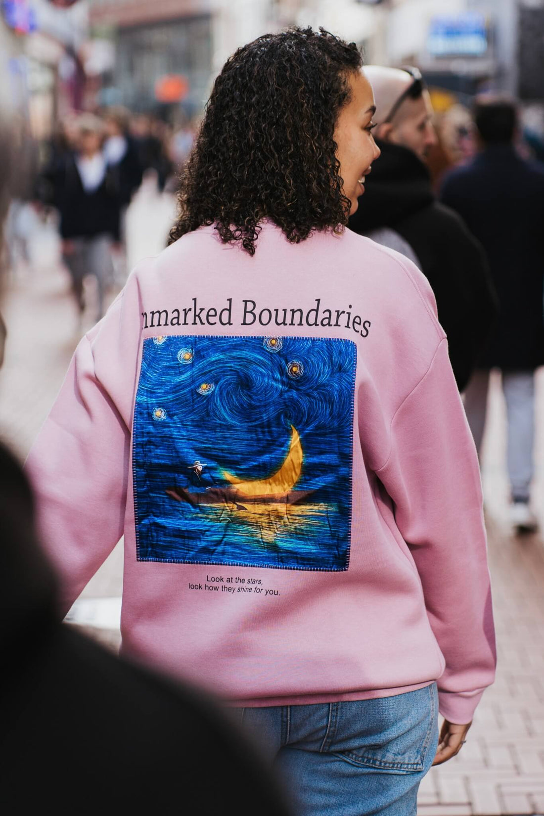 Woman wearing the Unmarked Boundaries pink sweatshirt on the streets of Amsterdam